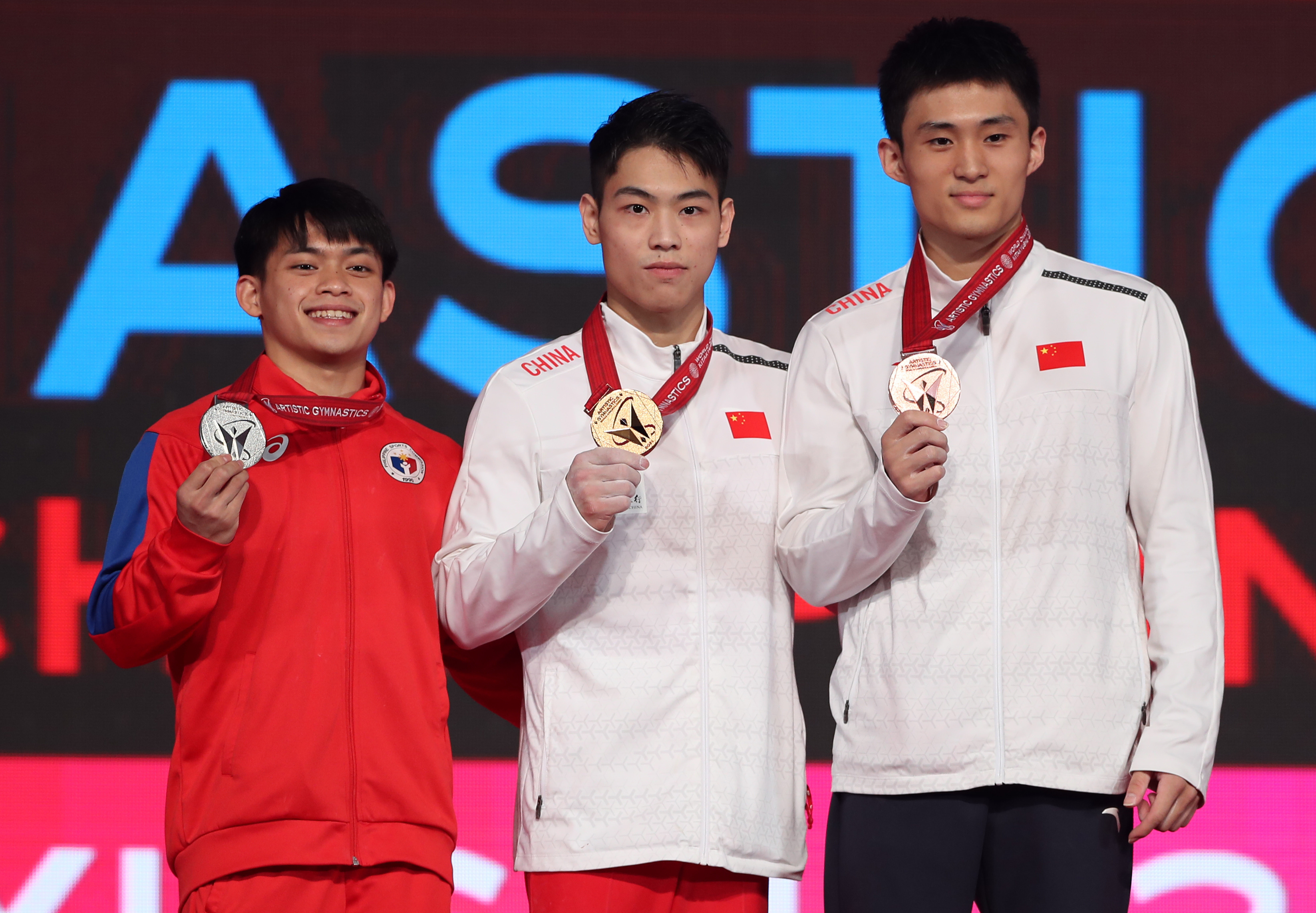 冠軍中國選手胡旭威（中）、亞軍菲律賓選手尤洛（左）和季軍中國選手侍聰在雙杠頒獎儀式上。新華社記者 杜瀟逸 攝