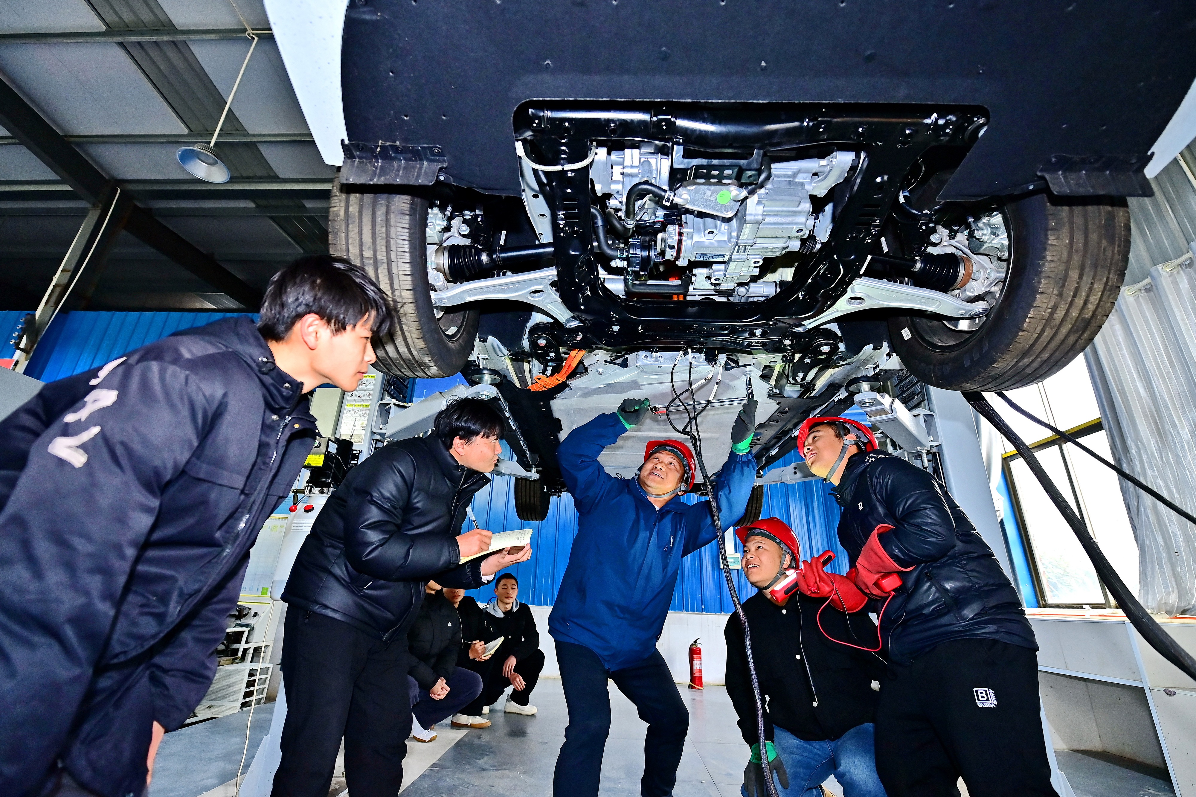 2025年2月17日，江西省宜春市，豐城市的一所技工學校實訓基地內(nèi)，新能源汽車運維專業(yè)學生在老師的指導下學習新能源汽車電池包檢修技術。