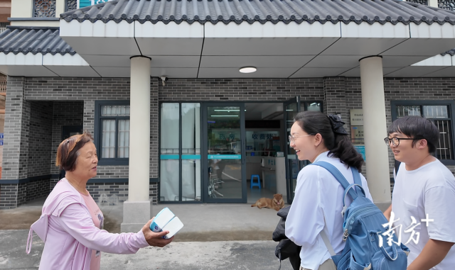 公共服務組成員王櫻潔（中）和張龍（右）在崖口村衛生室前跟村民打招呼。