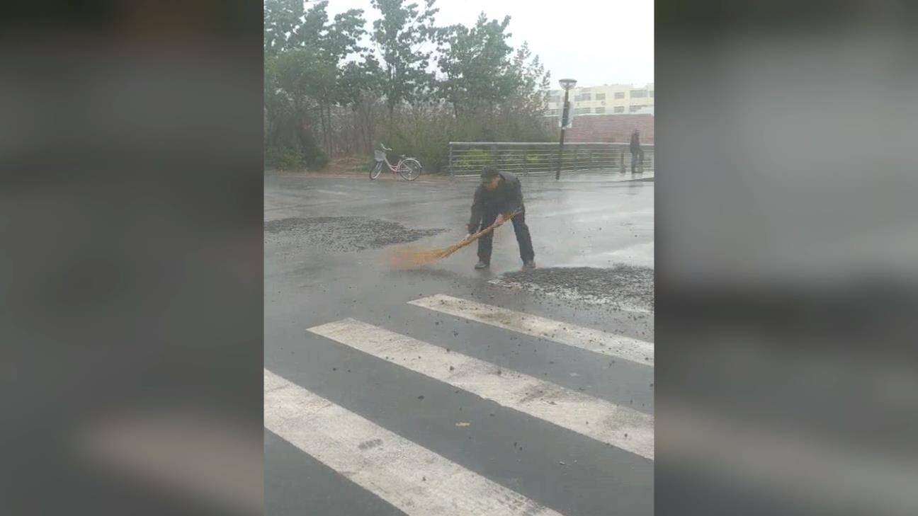 18秒丨暖心！滨州雨后一处路面散落大量碎石子 一老人用扫帚清扫干净