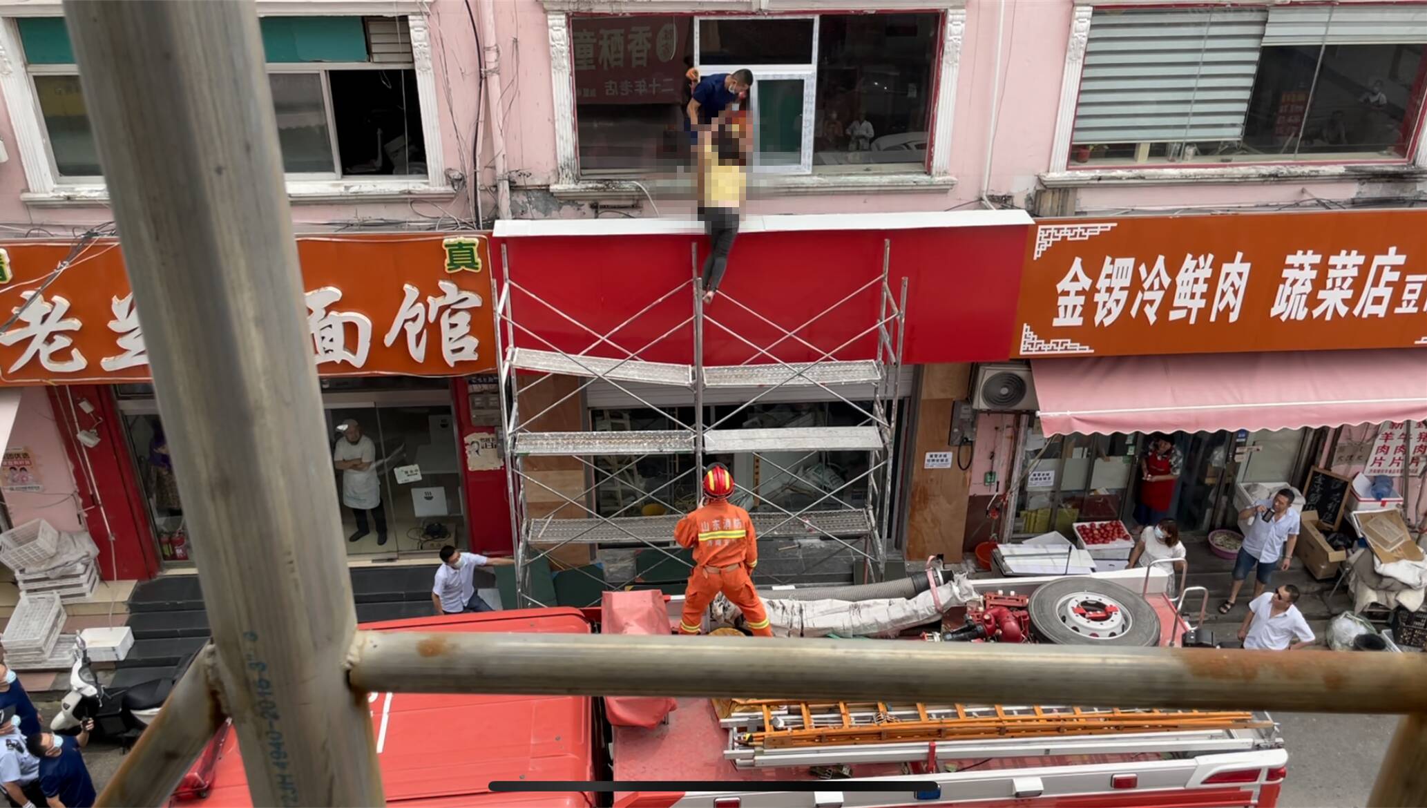 济南一女子因家庭纠纷爬上五米高脚手架 消防员飞身救下