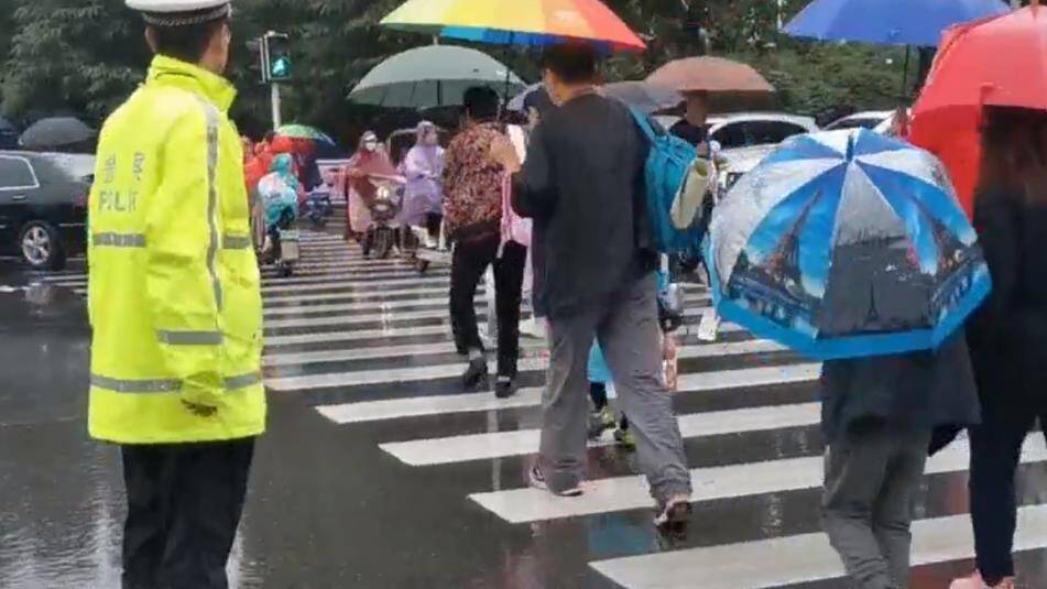 滨州邹平交警冒雨坚守护学岗 为学生撑起“平安伞”