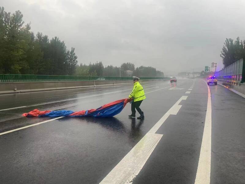 雨天篷布横在高速路上 济南交警冒雨排除险情