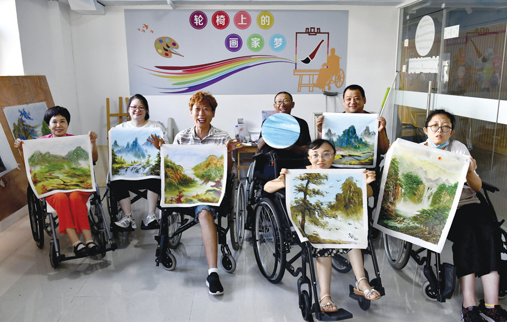 在威海长城爱心大本营，残疾人学员和指导老师拿着油画作品合影留念。